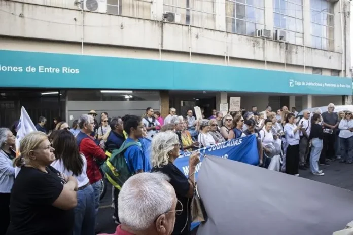 Grupo de personas adultas mayores conversando en un banco de plaza, representando la discusión sobre el sistema previsional.