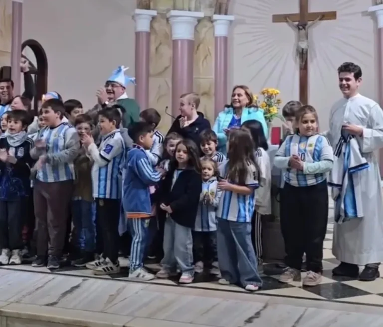Niños con camisetas de la Selección Argentina y sacerdote con gorro celeste y blanco al pie del altar en parroquia Santa Teresita de Gualeguaychú